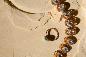 Stylish jewelry on sand, top view