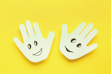 Palms with happy faces on yellow background. Friendship Day celebration