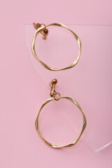 Glass splinter with golden earrings on pink background