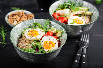 Breakfast oatmeal porridge with boiled eggs, avocado, tomatoes and green herbs. Healthy balanced food.