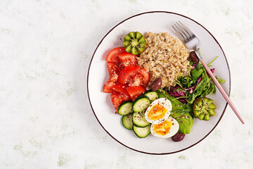 Breakfast oatmeal porridge with boiled eggs, fresh salad and kiwi. Healthy balanced food. Top view, overhead