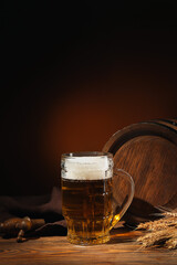 Mug of cold beer and wooden barrel on table against dark background
