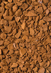 Zbliżenie na granulki kawy rozpuszczalnej tworzące zwartą powierzchnię wyglądającą jak kamienie.