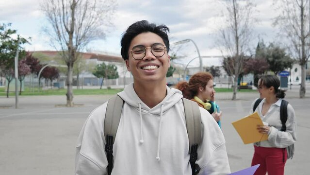 Portrait of smiling Student in University campus - Young Asian man with eyeglasses smiling outdoors