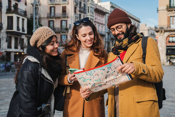 Group of tourists reading a map to found the location of a european monument. Three young travelers...