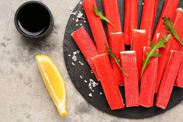 Slate board with tasty crab sticks and sauce on grunge background, closeup © Pixel-Shot