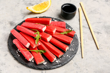 Slate board with tasty crab sticks on grunge background © Pixel-Shot