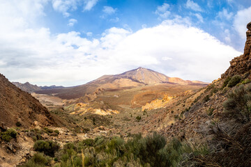 Experience the Teide National Park with a breathtaking panoramic view of the majestic Teide volcano, featuring iconic Roque del Garcia rock formation in the distance, all set against a overcast sky.