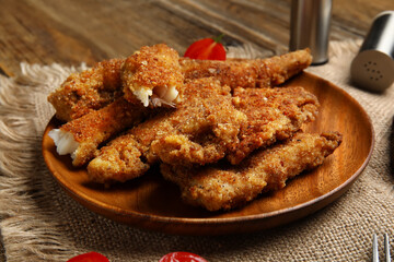 Plate of tasty fried codfish on wooden background, closeup