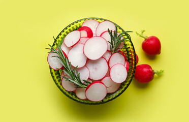 Bowl with sliced radish and rosemary on yellow background