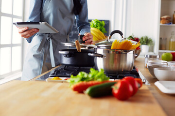 Young woman using a tablet computer to cook in her kitchen.