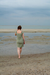 Young woman in dress is standing in front of the sea