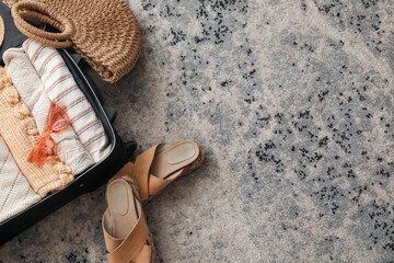 Suitcase with summer clothes and accessories on color carpet