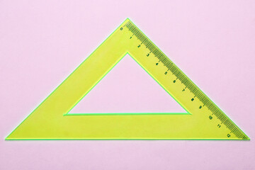 Yellow triangle plastic ruler on pink background
