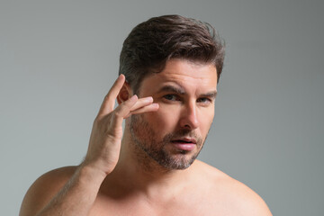 Obraz premium Close-up portrait of perfect brunet man touching chin and skin. Handsome man touching face in gray studio isolated background. Perfect skin. Man cosmetic, skin treatment. Hygiene skin care male face.