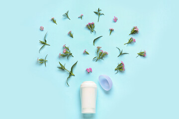 Deodorant bottle and flowers on blue background