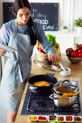 Woman baking at home following recipe on a tablet.