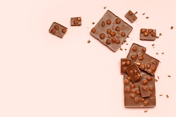 Sweet tasty chocolate with nuts on  light pink background