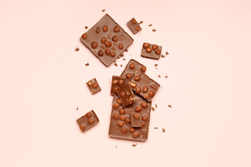 Sweet tasty chocolate with nuts on  light pink background