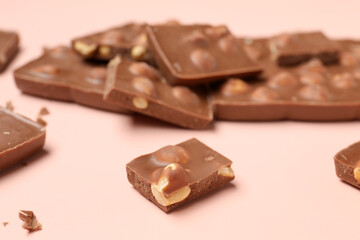 Sweet tasty chocolate with nuts on  light pink background, closeup