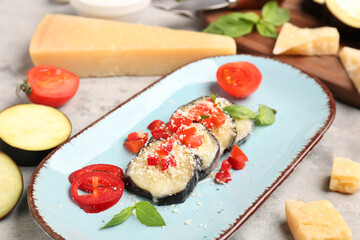 Plate with tasty baked Eggplant Parmesan and ingredients on grunge background