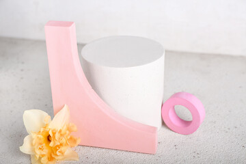 Decorative plaster podiums with flowers on grunge table against white background
