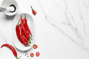 Plate with fresh chili peppers on white marble background