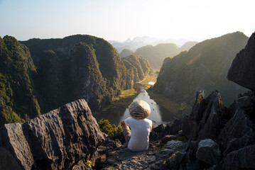 A beautiful young man travels to Southeast Asia to enjoy stunning views of Ninh Binh in Vietnam - obrazy, fototapety, plakaty