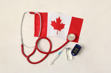 Flag of Canada with stethoscope, syringe, ampule and glucometer on white background