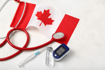 Flag of Canada with stethoscope, syringe, ampule and glucometer on white background