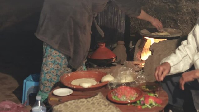 Berber family in old kitchen with wood oven preparing traditional moroccan food