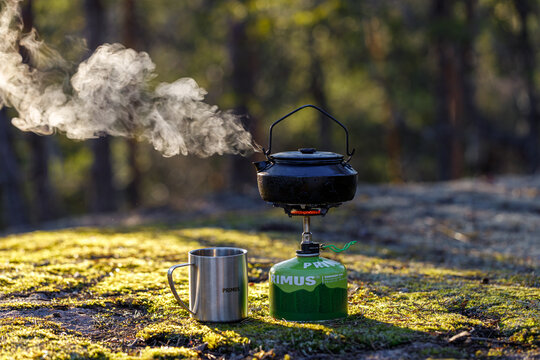 IMATRA, FINLAND - 19 APRIL, 2023: Kettle boiling on a gas stove in the forest. Background of the forest is blurred.
