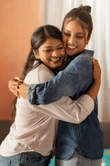 Two smiling young women hugging each other in living room