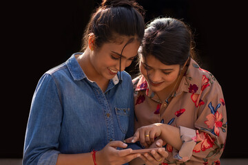 Two young women using mobile phone together