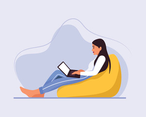 light-skinned girl with long hair sits on a bean bag chair with a laptop