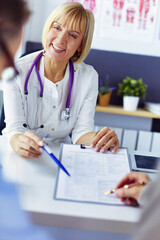 Doctor and patient examining a file with medical records, she is sitting on a wheelchair.