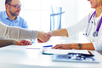 Obraz premium Female doctor shaking a hand in her office.