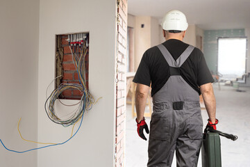Electrician man. Builder with his back to camera. Electrical engineer. Guy in unfinished room....