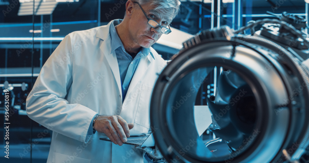 Poster Middle Aged Industrial Turbine Specialist Working on an Innovative Invention. Scientist Using a Laptop Computer to Develop a High Tech Prototype Electric Jet Motor