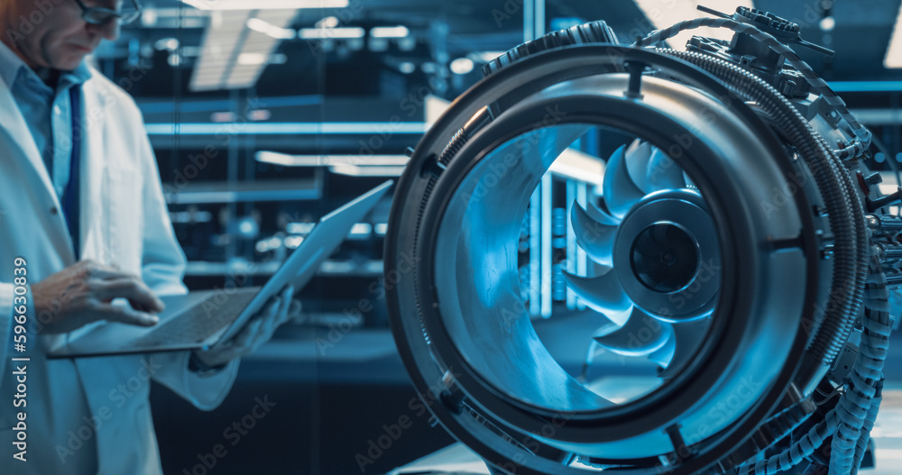 Poster High Tech Prototype Jet Engine in a Technological Startup Facility. Scientist in White Coat Using a Laptop Computer in the Background