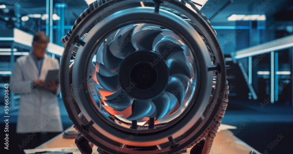 Poster industrial engineer working on a futuristic jet engine, standing with laptop computer in scientific 