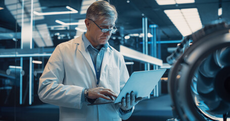 Professional Adult Engineer Using a Laptop Computer, Analyzing and Checking How a Modern Electric...