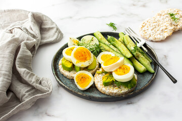 Healthy breakfasts, rice cakes with avocado and boiled eggs with dill and cucumber with spices,...