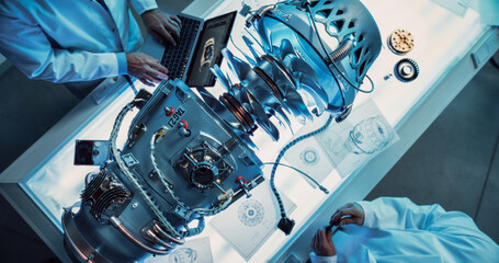 Two Professional Jet Engine Researchers Discussing Work, Using Laptop Computer and Checking...