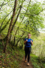Naklejka na ściany i meble Pretty young woman in sportswear doing a trail in the mountains near the Holtzate Gorge