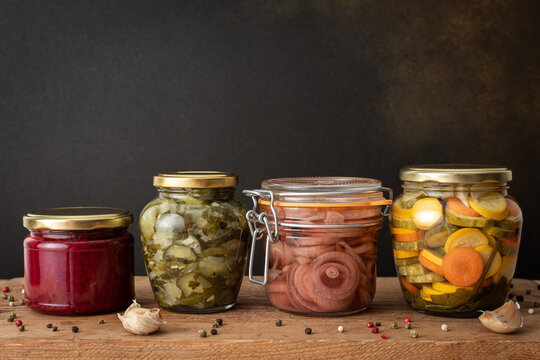 Preserving vegetables for the winter, canned vegetables in jars on a wooden table against a brown wall, pickled or fermented vegetables, copy space