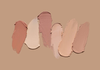 Concealer or foundation assortment palette on beige nude background