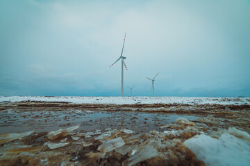 icy puddle on snowy fields with windmills in the background