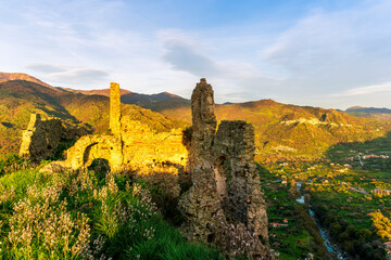 picturesque view from a mountain with ancient monument or castle ruins to a green valley with amazing mountains on background of landscape and beautiful cloudy sky