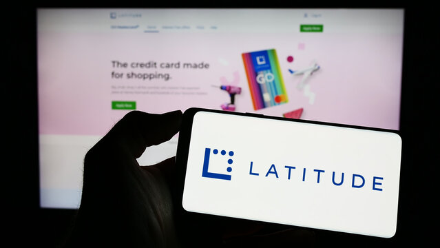 Stuttgart, Germany - 04-23-2023: Person holding cellphone with logo of Australian financial company Latitude Group on screen in front of business webpage. Focus on phone display.